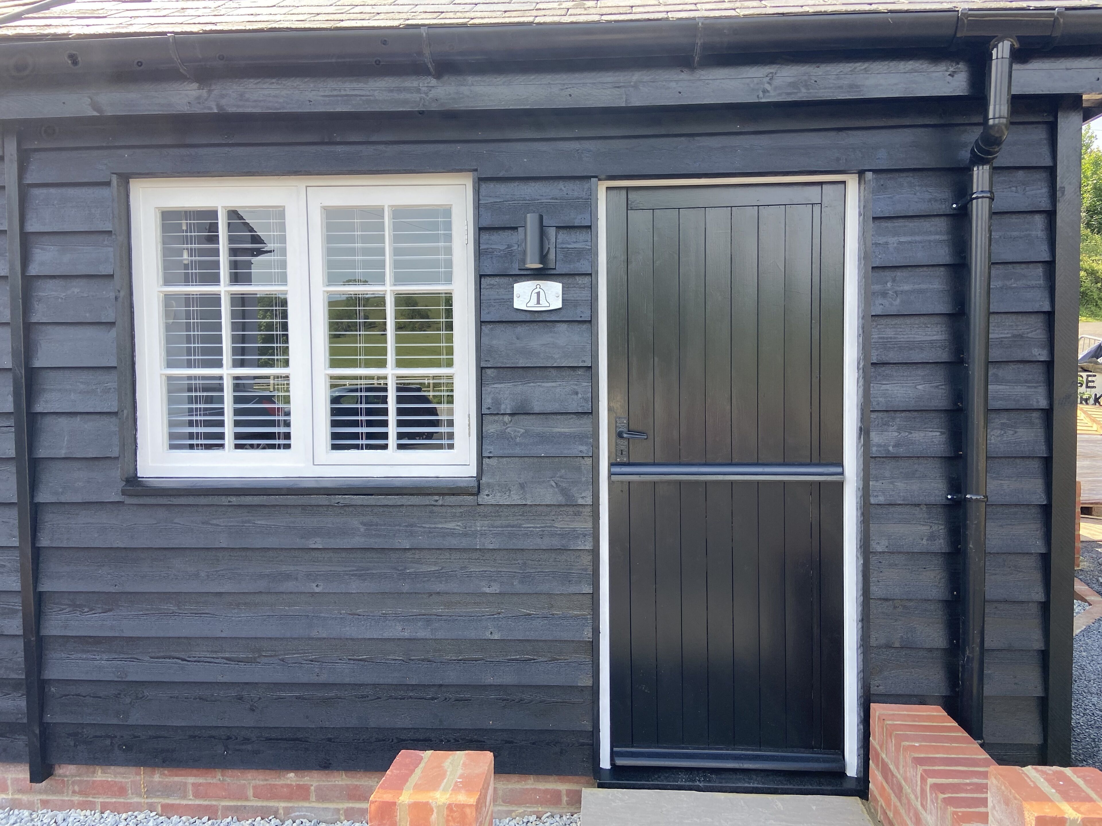 A dark wooden building with a white-framed window and a black door.