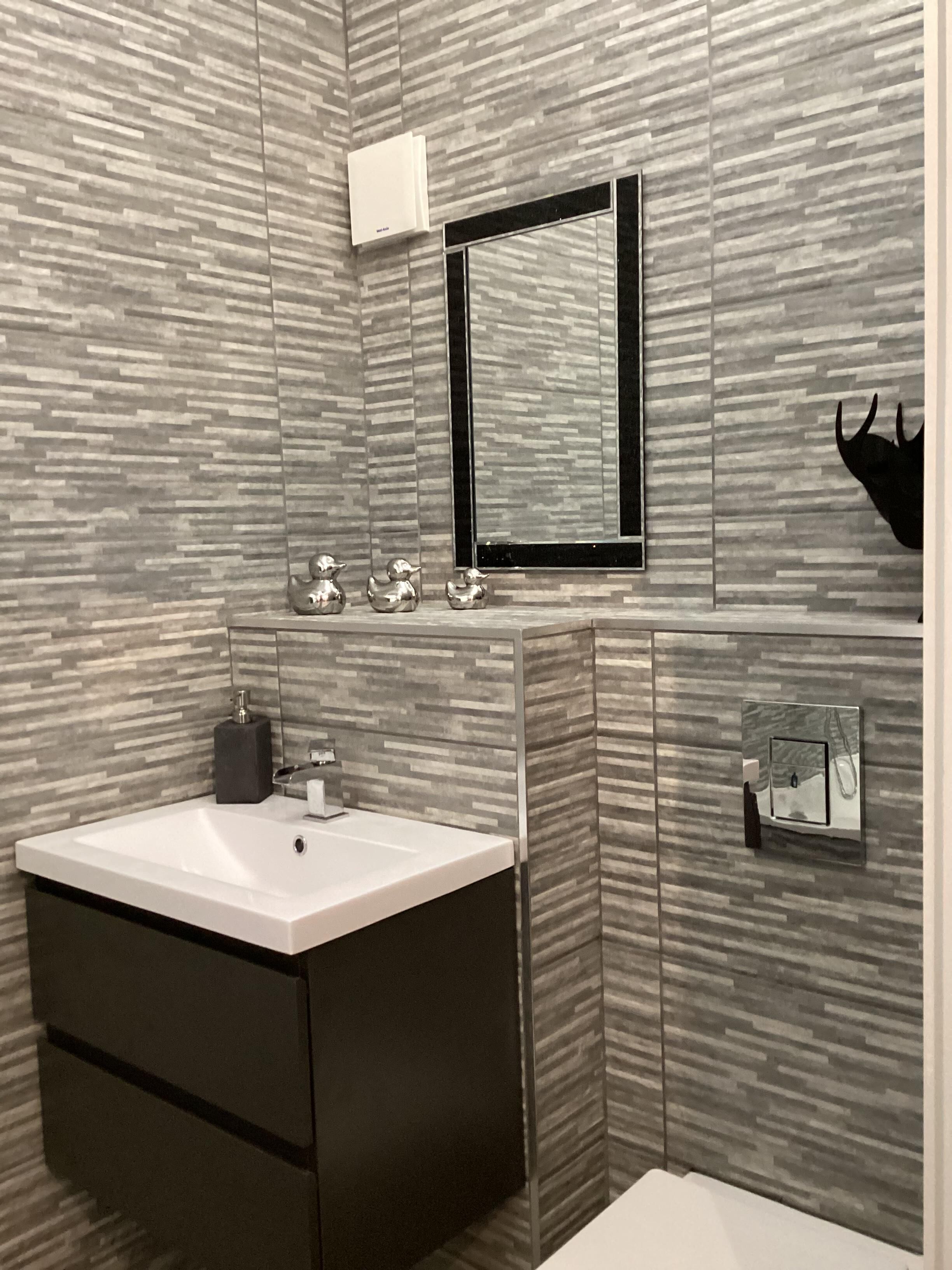 Un baño moderno con un lavamanos rectangular, un espejo y un inodoro.