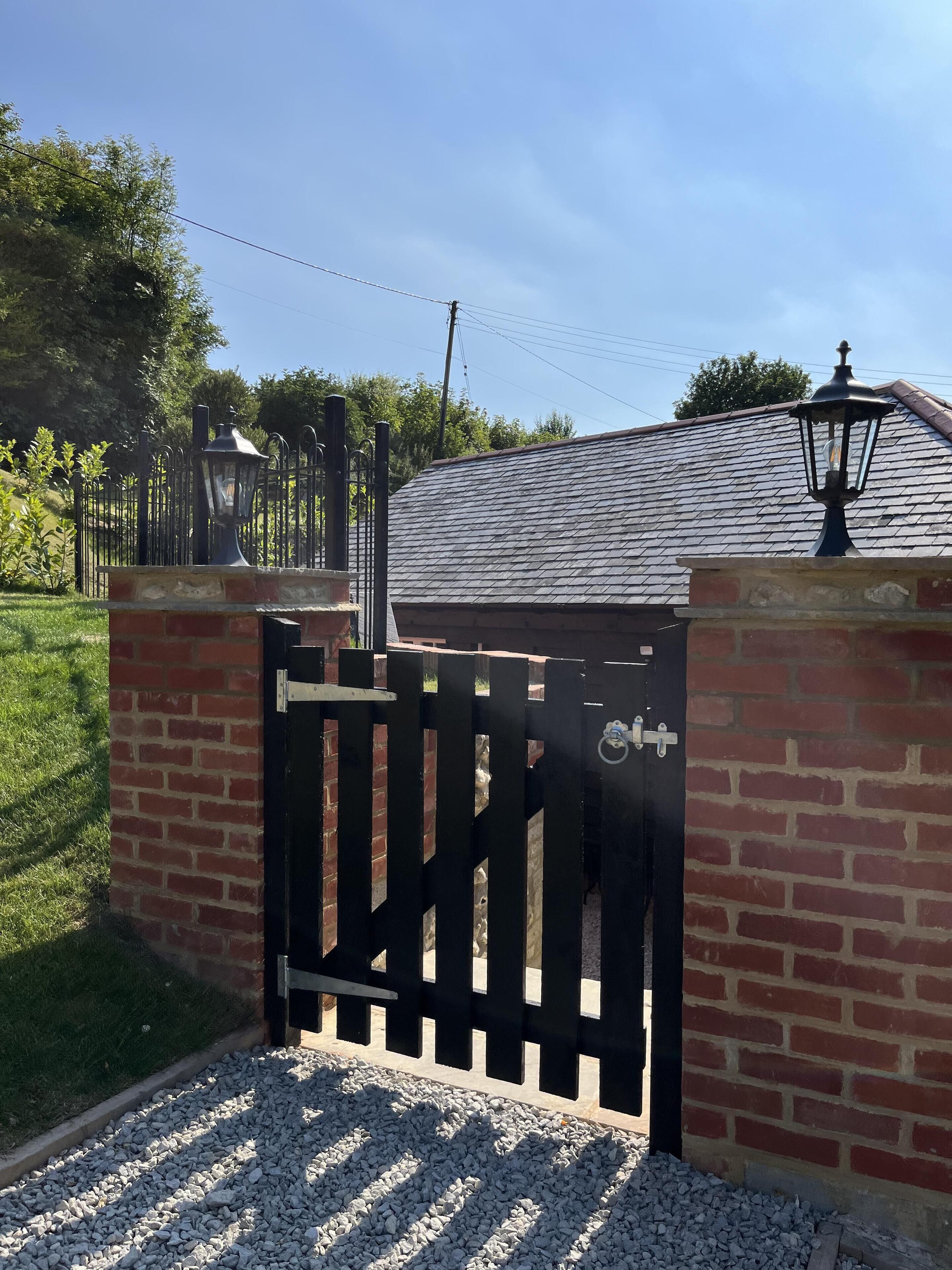 A gated entrance with a brick wall and a metal gate.