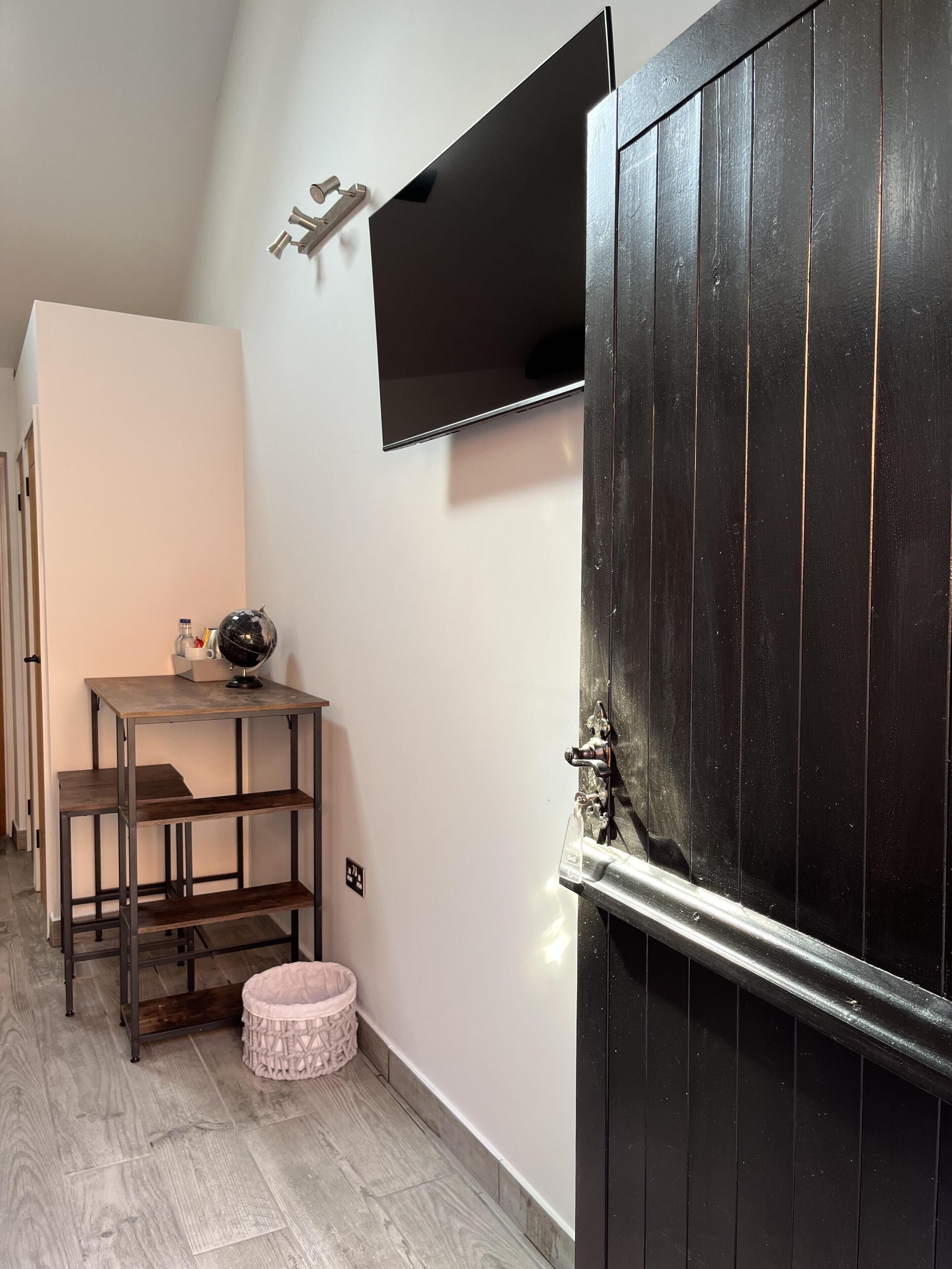Un couloir avec une porte noire, une petite table sur laquelle repose un globe terrestre et une étagère.