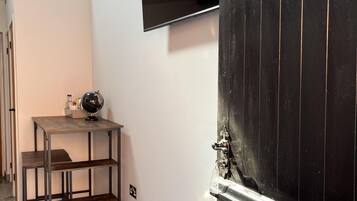 Un couloir avec une porte noire, une petite table sur laquelle repose un globe terrestre et une étagère.