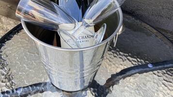 A bottle of champagne in a metal bucket with glasses.