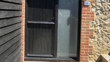 A black door with a glass panel, a stone wall, and a small step leading to the entrance.