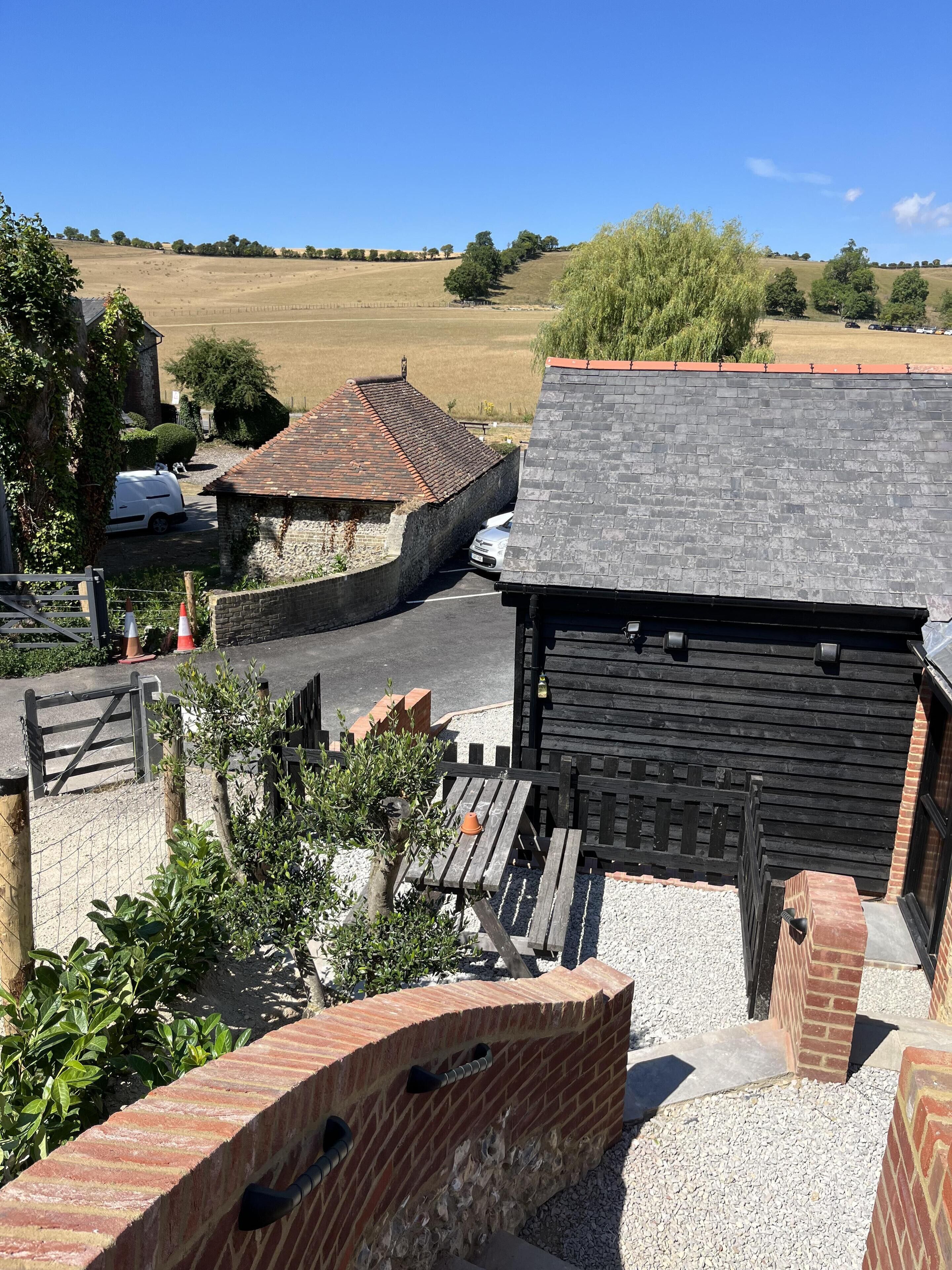 A rural setting with a stone building, a wooden fence, and a gravel path.