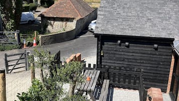 A rural setting with a stone building, a wooden fence, and a gravel path.
