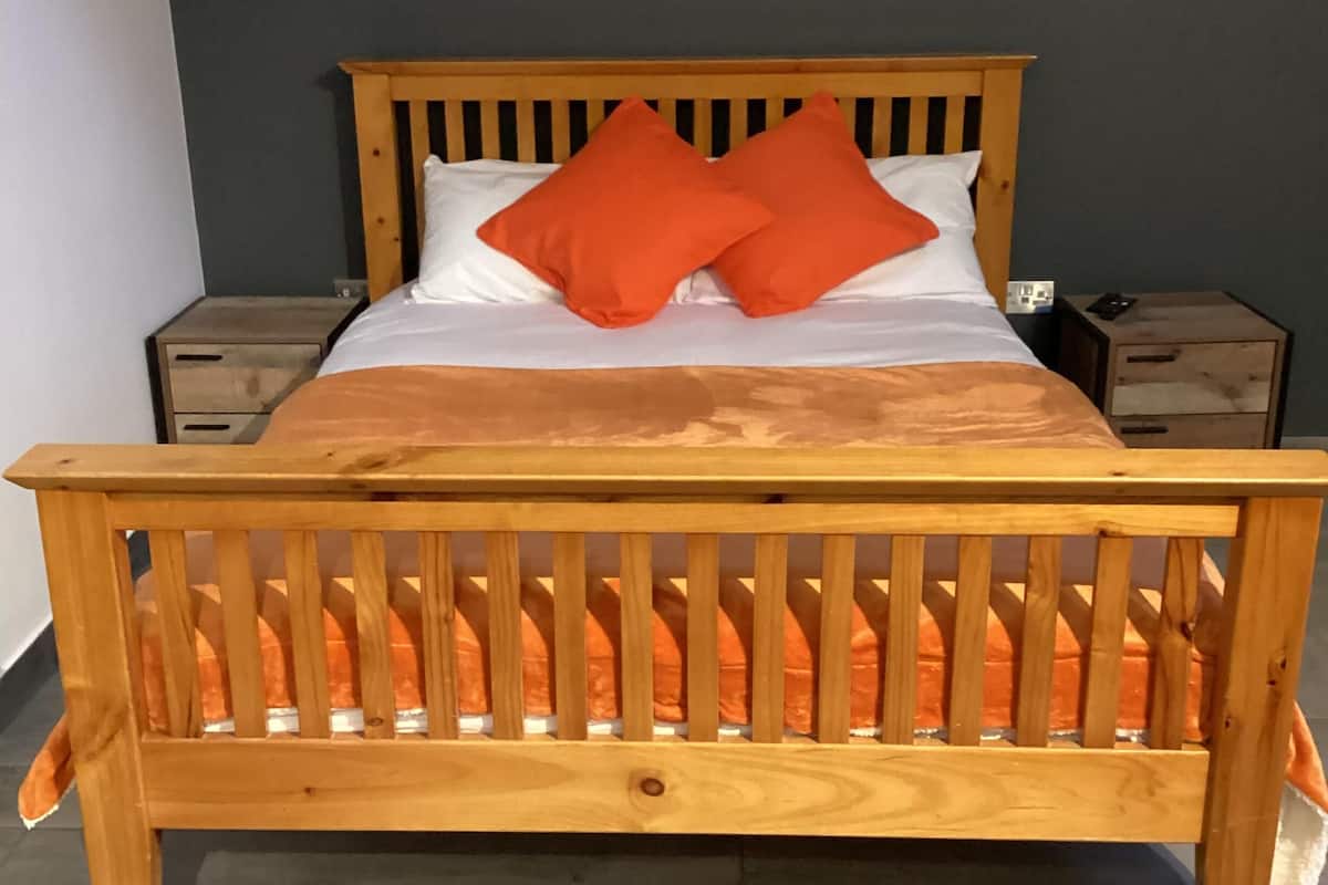 Ein hölzernes Bett mit Kopfteil, zwei Kissen und zwei Nachttischen.