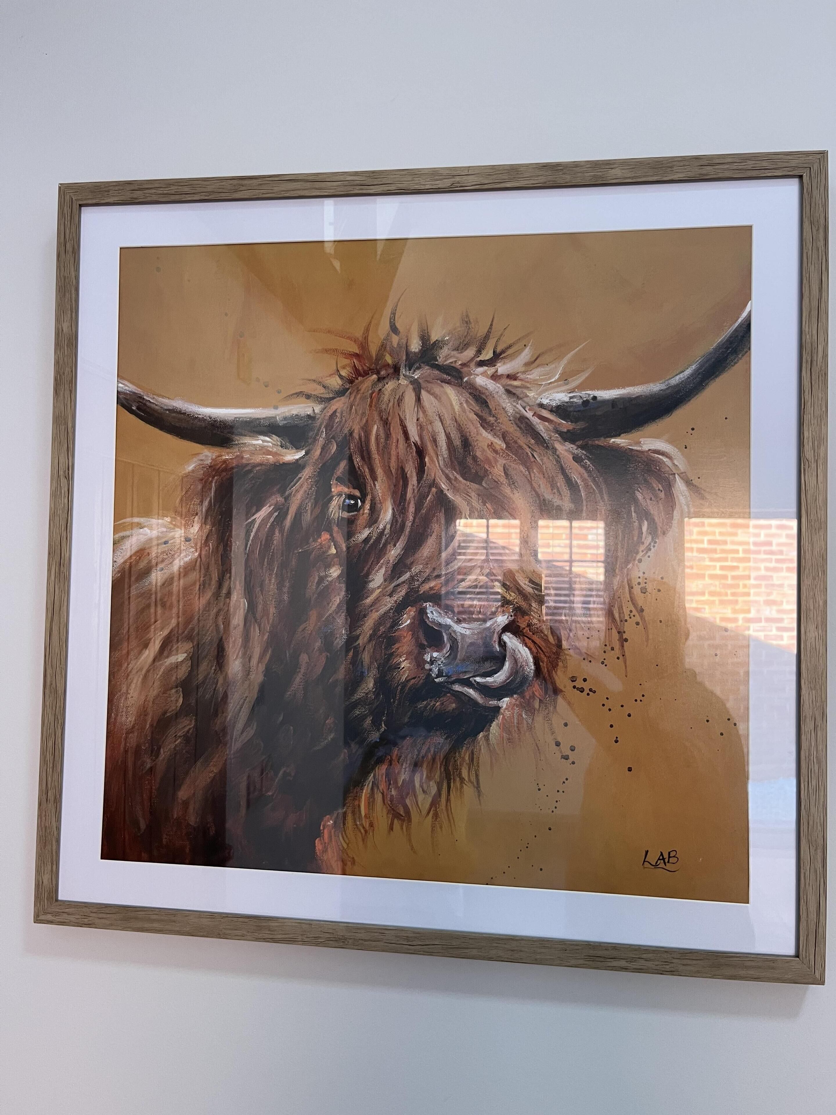 A framed painting of a yak with a wooden frame.