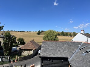 Paisaje rural con cielo azul despejado, un campo y un edificio blanco de techo rojo.