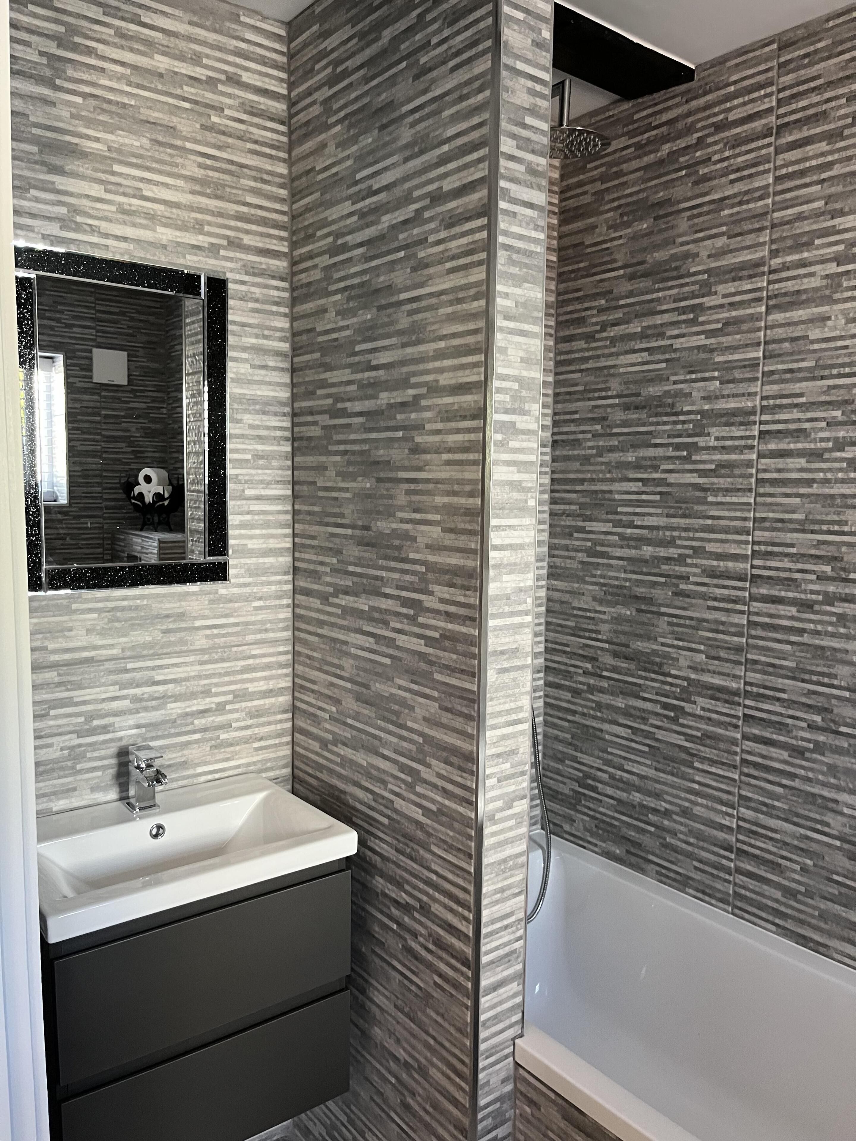A modern bathroom with a rectangular mirror, a white sink, and a bathtub.