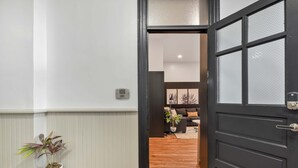A hallway leading to a living room with a dark door, a potted plant, and a sign indicating unit 106. - A Cleveland Modern and Historic Apartment (Cleveland)