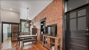 A modern kitchen with a brick wall, wooden flooring, and a black door. - A Cleveland Modern and Historic Apartment (Cleveland)