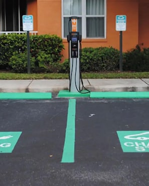 A parking space with a green electric vehicle charging station.