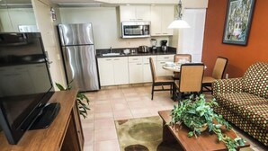Een kleine keuken met moderne apparatuur, een eethoek met tafel en stoelen, en een bank met een patroon.