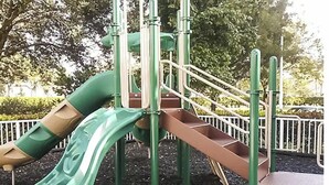 Een speeltuin met een groene glijbaan en een bruine klimconstructie.