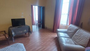Una sala de estar con un sofá, una mesa y un televisor, y una silla.