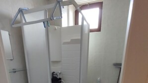 Un baño pequeño y funcional con cabina de ducha, inodoro y lavabo.
