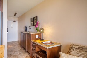 A kitchen with wooden cabinets, a marble countertop, a vase with flowers, and a wall-mounted light fixture.