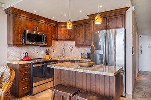 A modern kitchen with wooden cabinets, stainless steel appliances, and a granite countertop.