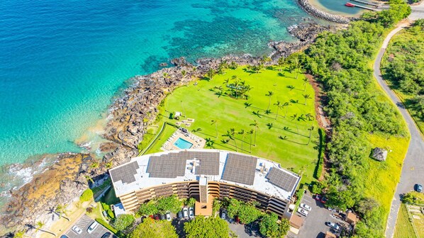 An aerial view of a resort with a pool, a golf course, and a rocky coastline.