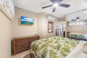 A bedroom with a bed, a dresser, a ceiling fan, a TV, and a mirror.