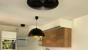 A modern kitchen with white cabinetry, a wooden island, and a black pendant light. - Cosy house close to Arcachon golf course. (La Teste-de-Buch)