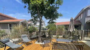 A wooden deck with lounge chairs and a table, surrounded by a wooden fence and trees. - Cosy house close to Arcachon golf course. (La Teste-de-Buch)