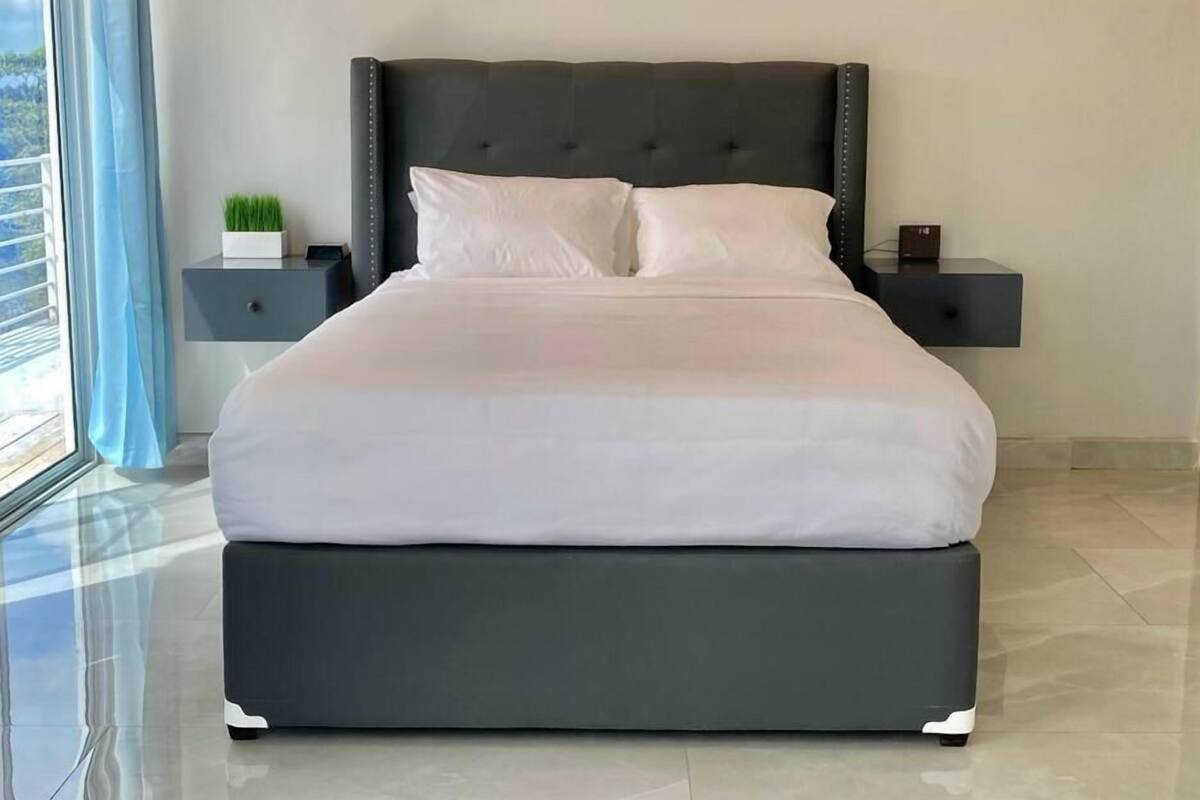 A modern bedroom with a large bed, a nightstand, and a bedside table.