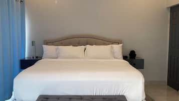 A bedroom with a large bed, bedside tables, a bench, and a ceiling light.