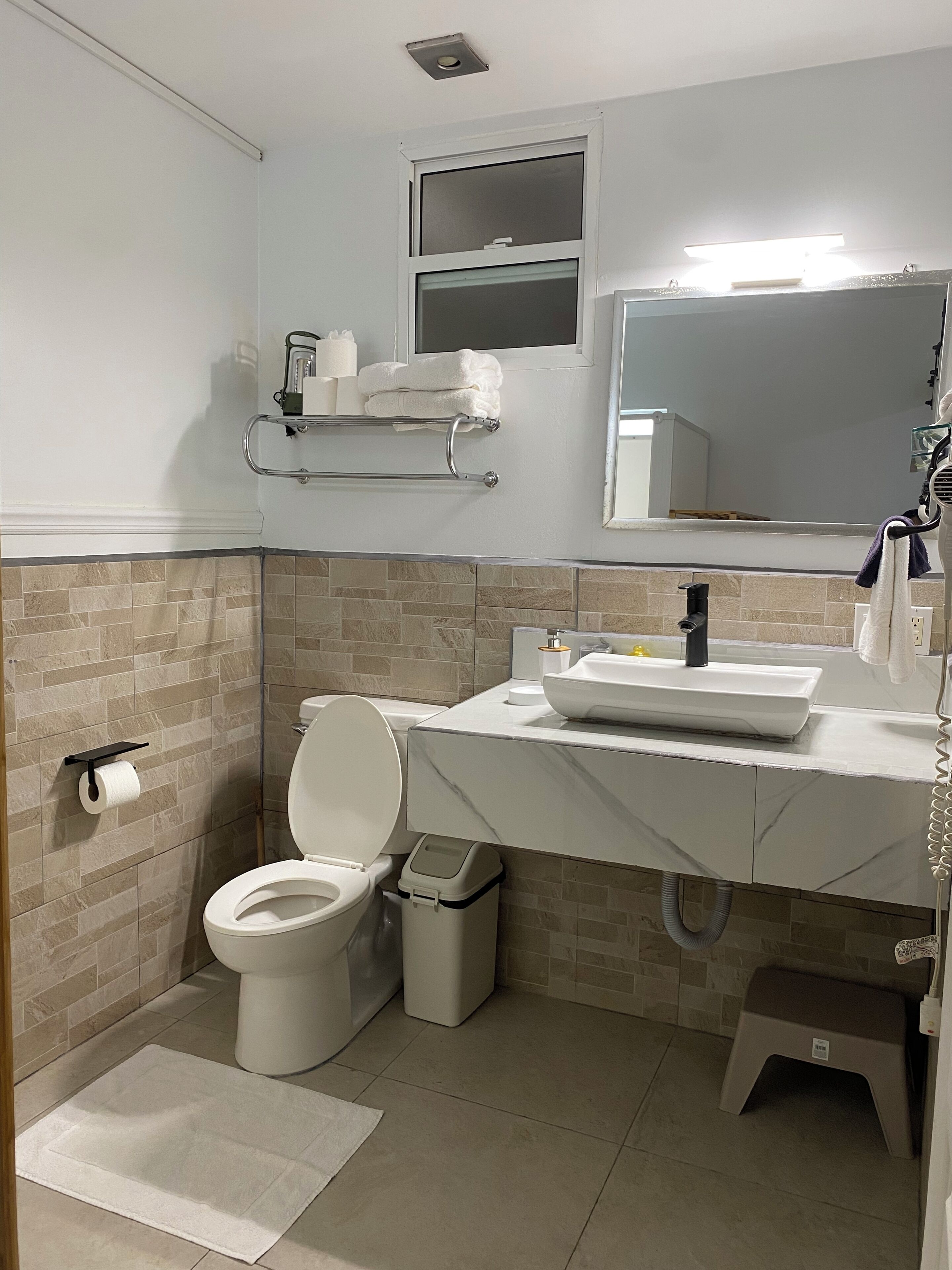 A bathroom with a toilet, sink, and mirror.