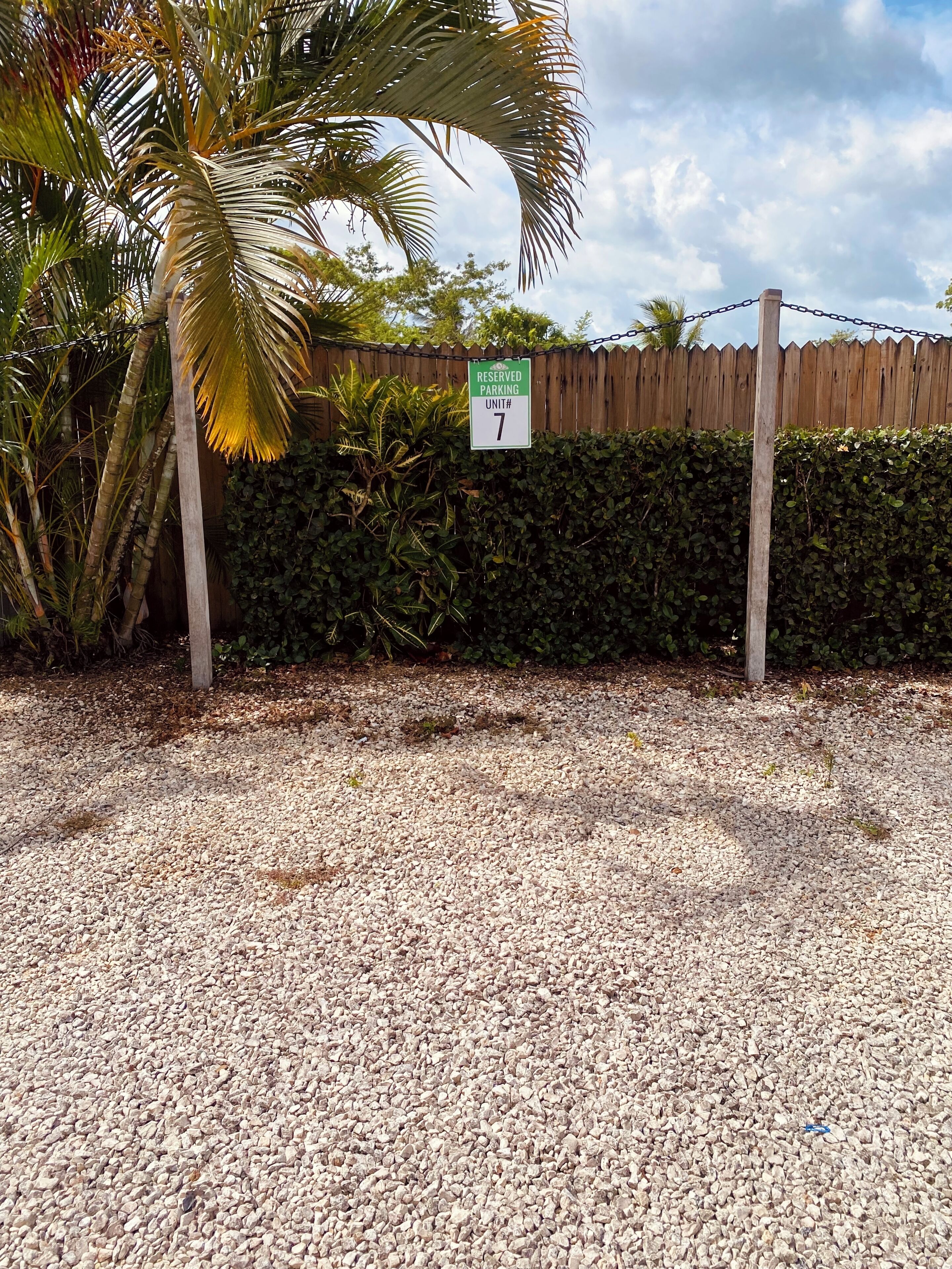 A parking sign with a number, surrounded by gravel and greenery.