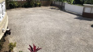 A rooftop patio with gravel flooring, surrounded by a wooden fence and various plants. - The Ansen Place (Belmopan)
