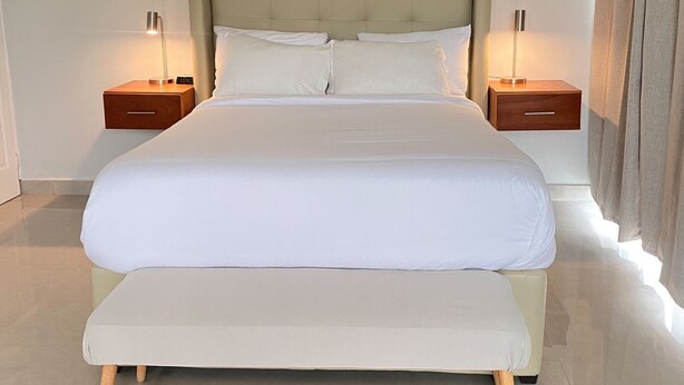 A large bed with a wooden frame, two bedside tables, and a headboard. - The Ansen Place (Belmopan)