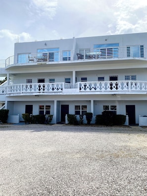 A multi-story building with balconies, a gravel driveway, and a clear sky. - The Ansen Place (Belmopan)