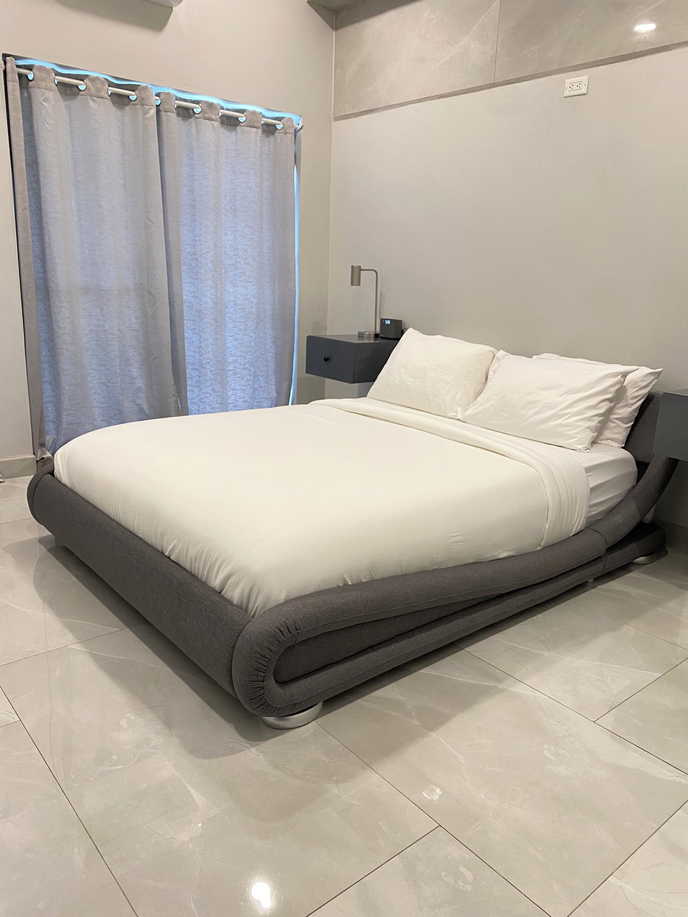 Een moderne slaapkamer met een groot bed, een nachtkastje en een stopcontact.