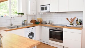 Une cuisine moderne avec des meubles blancs, un lave-linge encastré, un lave-vaisselle et un four.