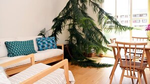 Un salon chaleureux avec un canapé, une table à manger et une grande plante d’intérieur.