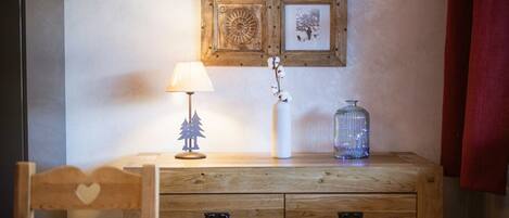 A wooden dresser with drawers, a lamp, and a vase with flowers.