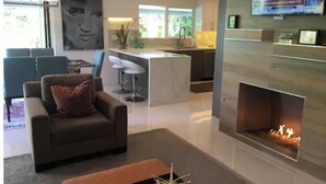 A modern living room with a sofa, a fireplace, and a TV mounted on the wall. - Mid-Century Private PoolSpa GolfResort LushGardens (New York)