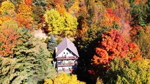 A two-story house surrounded by autumn foliage.