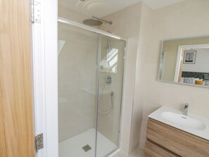 A modern bathroom with a glass-enclosed shower, a white sink, and a wooden vanity. - Foxton Penthouse (Whitby)