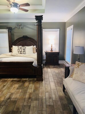 A bedroom with a four-poster bed, a wooden floor, a ceiling fan, and a nightstand with a lamp. - 7th Ave Manor, Remodeled 1930’s Manor just minutes from Historic Downtown Laurel (Laurel)