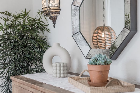 A wooden table with a white vase, a textured lamp, and a potted plant.