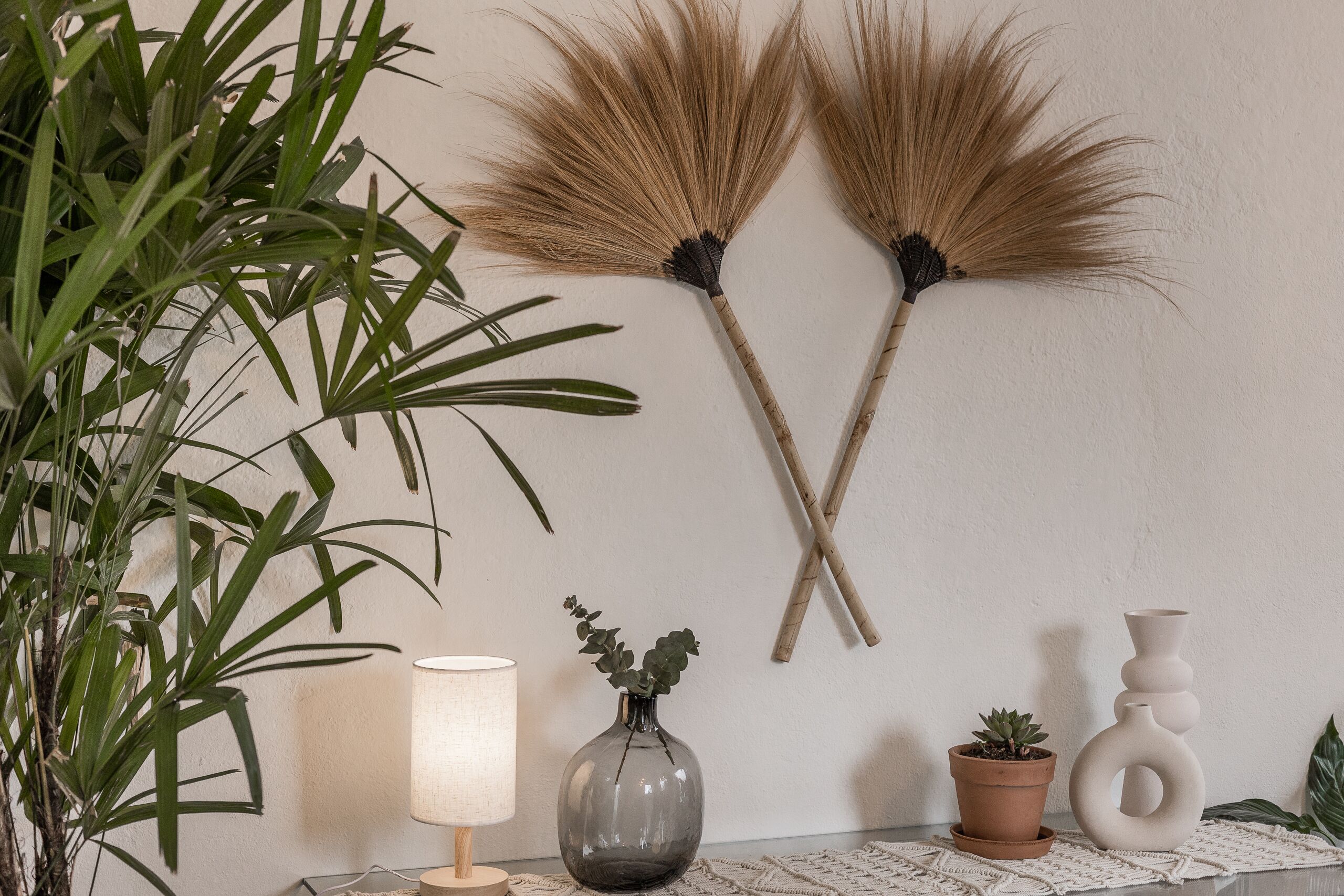 Ein Zimmer mit Blumentopf, Blumenamphore, Lampe und zwei Wanddekorationen.