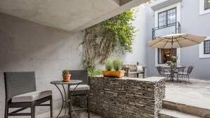 An outdoor patio area with wicker furniture, a stone wall, and a potted plant.