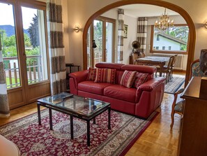 A living room with a red sofa, a glass coffee table, and a patterned rug. - Vintage (Annecy-le-Vieux)