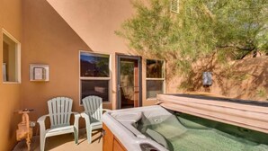 Un espacio de spa con un jacuzzi, dos sillas Adirondack y una ventana con vistas a un jardín.