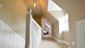 A narrow hallway with white railings, a sloped ceiling, and a light fixture. - Achanlochan Farm (Taynuilt)