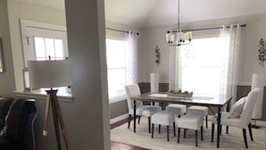 Un comedor con mesa de madera, seis sillas y una araña.
