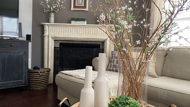 Un salón con chimenea, un sofá, un televisor y elementos decorativos como jarrones y una planta.