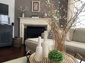A living room with a fireplace, a sofa, a TV, and decorative items including vases and a plant. - Charming 1 floor  house!!!! (spring)